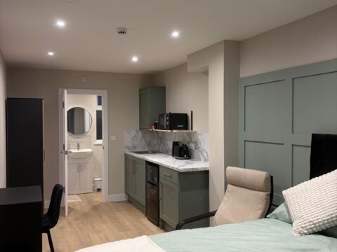 Studio flat or bedroom suite featuring green shaker style kitchenette with marble effect worktop