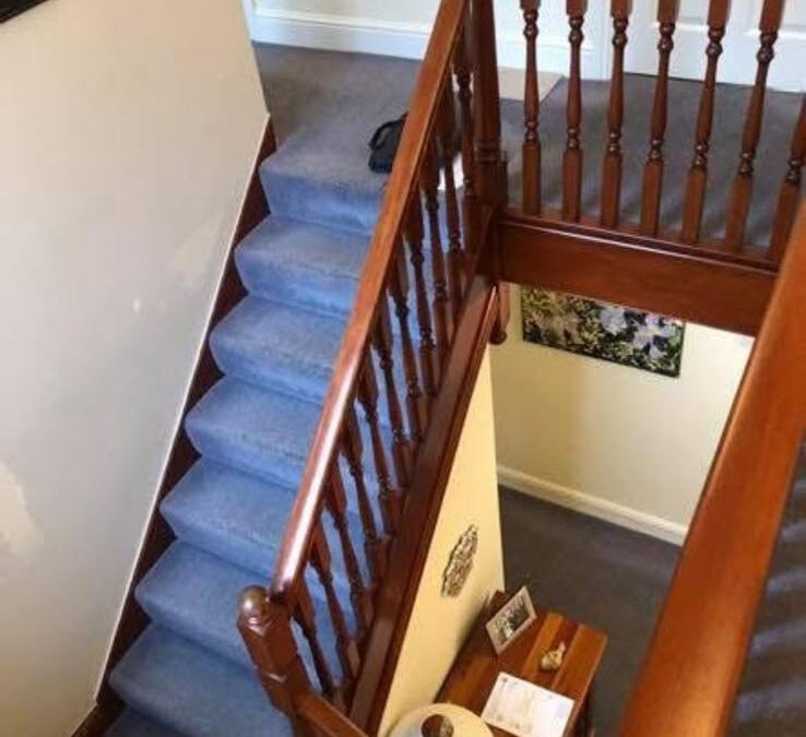 Mahogany staircase with turned spindles and a blue carpet
