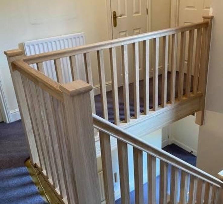 Landing balustrade with a timber handrail and white spindles