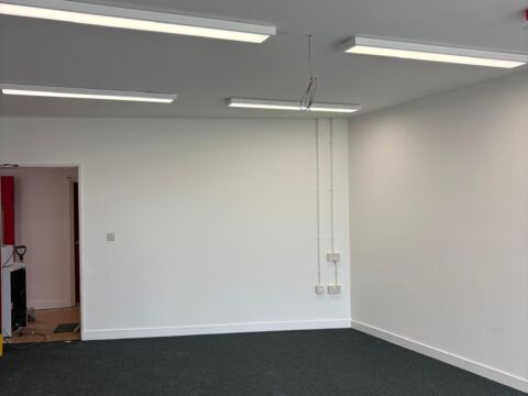 Commercial office space with newly fitted dark grey carpet and LED strip lighting installed on the ceiling