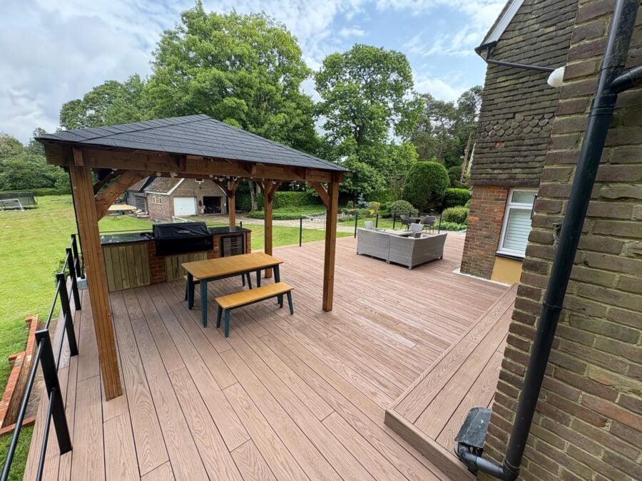 Composite decking installation in wood effect finish featuring timber framed gazebo with slate roof, metal railings