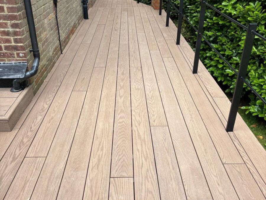 Composite decking installed in light oak wood effect with black metal railings and posts