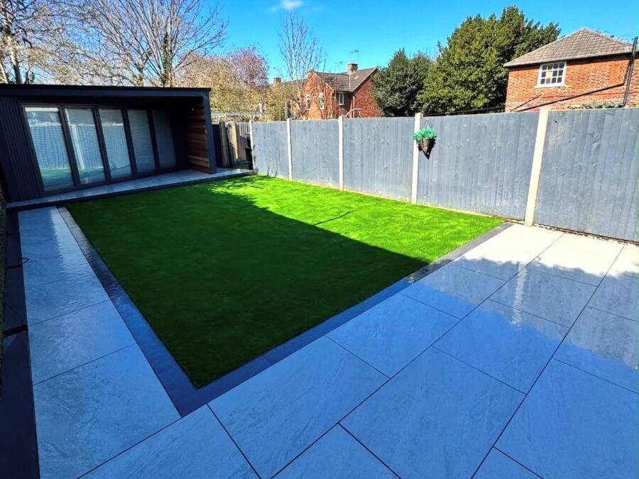 Porcelain patio and artificial lawn beside a garden room