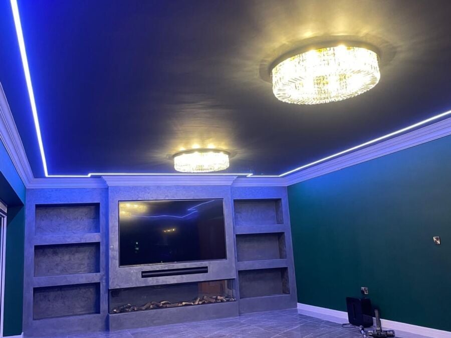 Modern living room interior featuring blue LED strip lighting in ceiling coving, flush mounted crystal ceiling lights