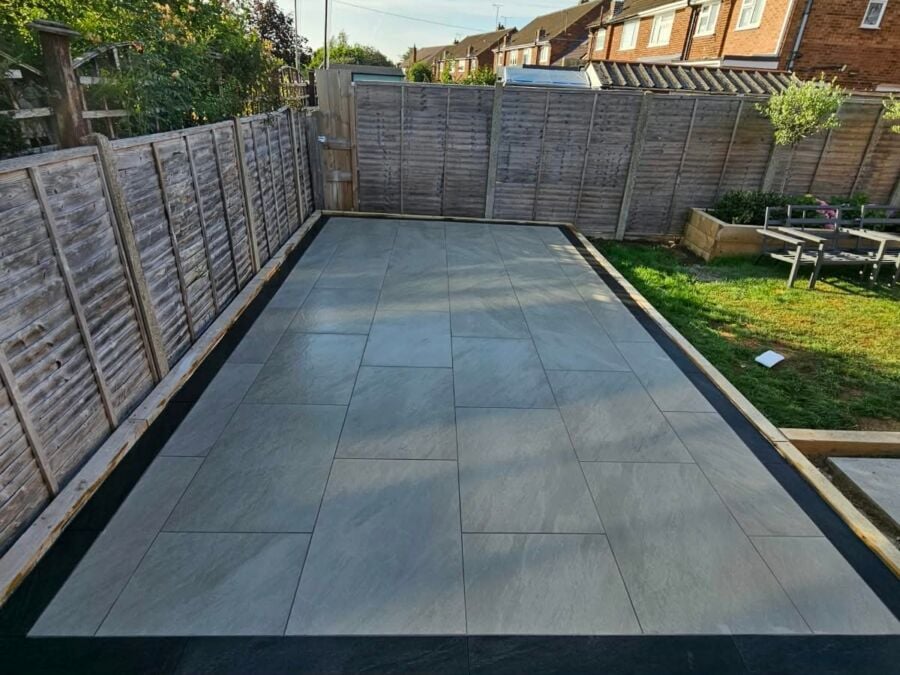 Newly laid patio featuring large format grey porcelain tiles with timber edging in a residential garden