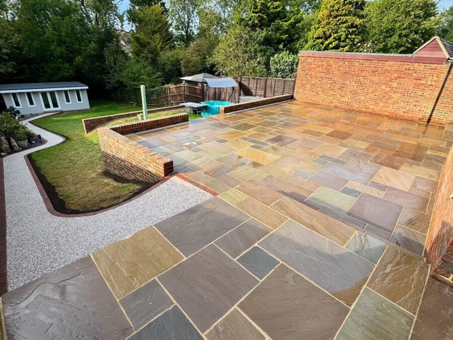 Sandstone patio with raised brick planters and a gravel path