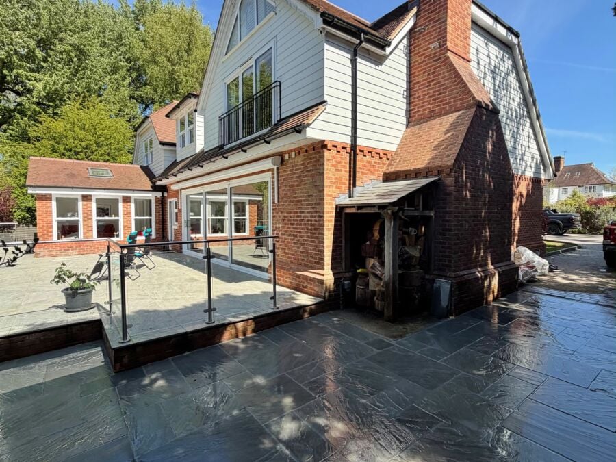Dark porcelain patio with a glass balustrade at the rear of a house