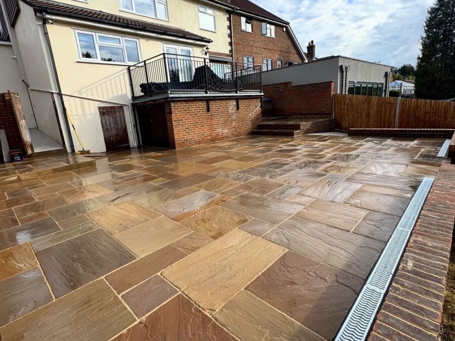 Sandstone patio with a drainage channel at the rear of a house