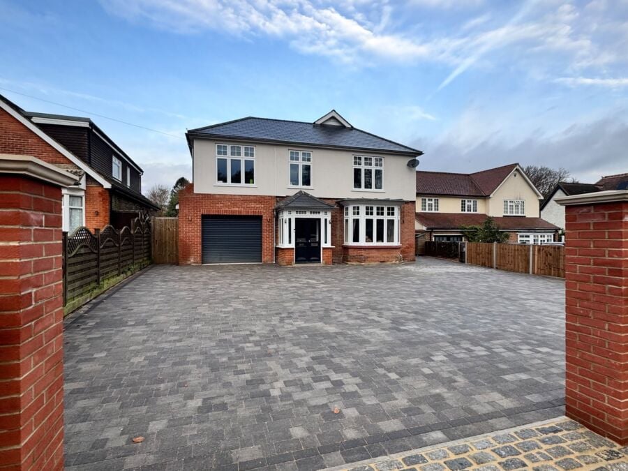 Large block paved driveway with a cobbled entrance in front of a detached house