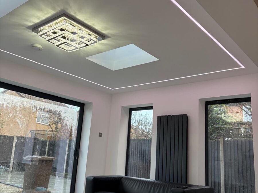 Modern extension interior featuring a recessed ceiling detail with integrated pink LED strip lighting, decorative crystal ceiling fixture