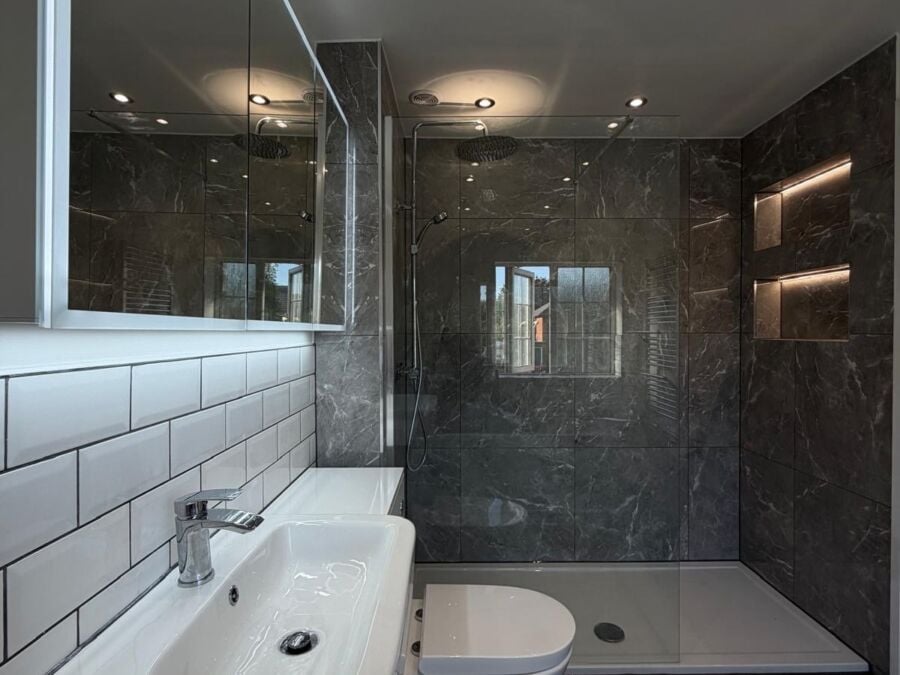 Shower room with marble effect tiles, white metro tiles and a lit niche