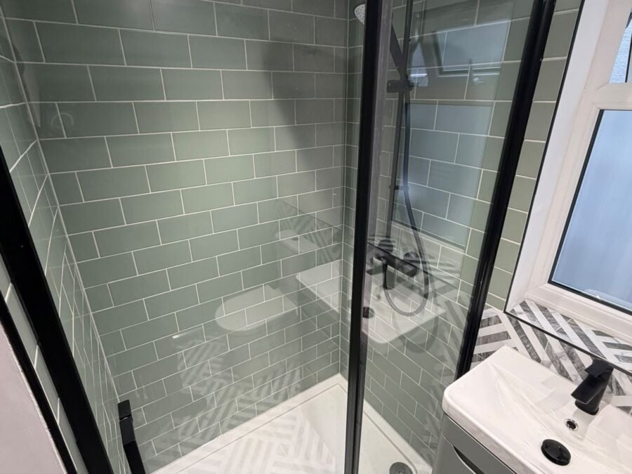 Shower enclosure with black frame, green metro tiles and herringbone floor