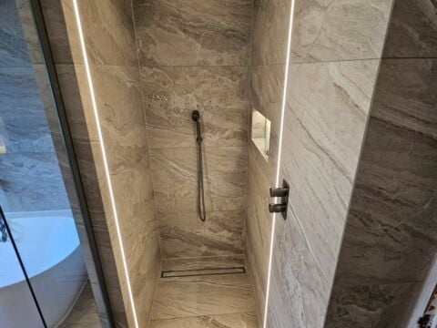 Walk in shower enclosure with large format marble effect porcelain wall tiles in beige tones