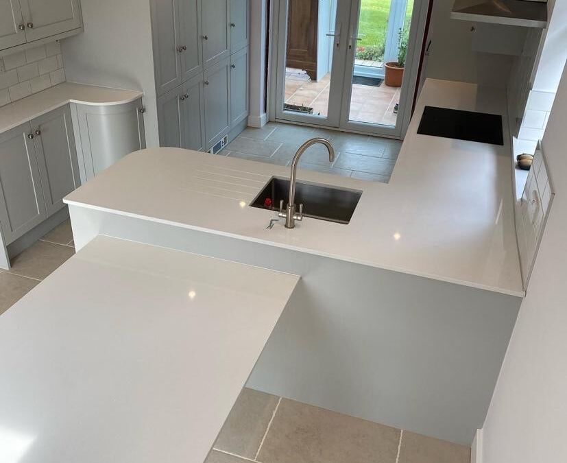 Shaker kitchen with white quartz worktop and undermount sink, leading to garden doors