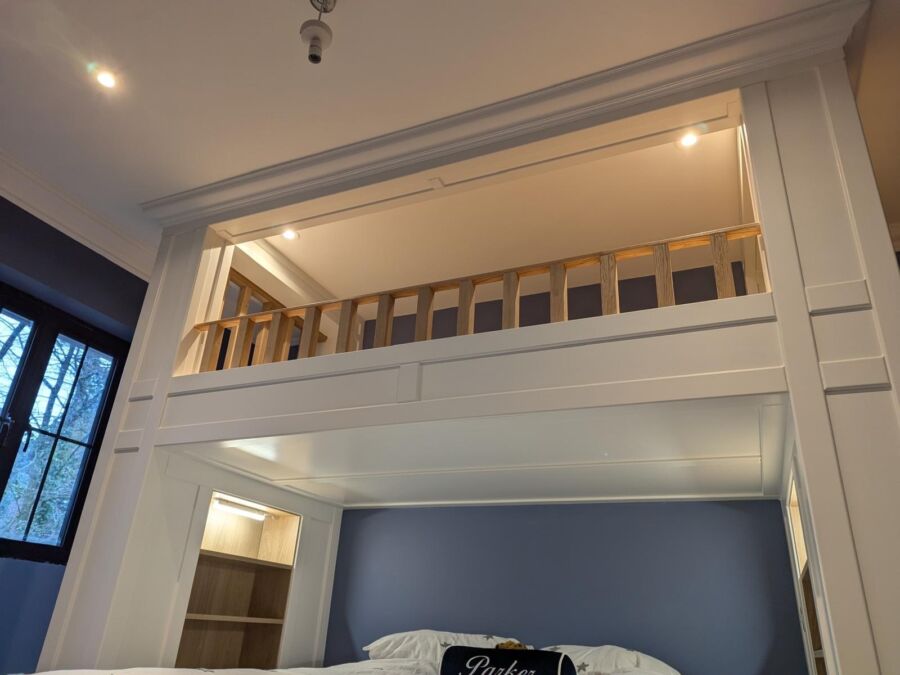 Bespoke mezzanine sleeping platform with timber balustrade built above a bedroom