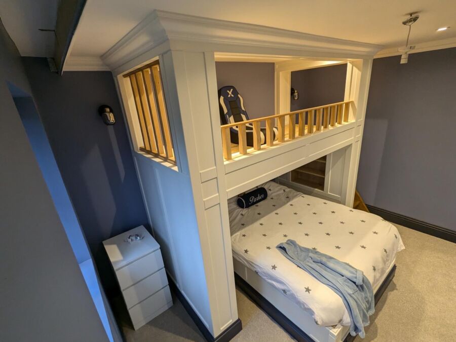 Bedroom with a bespoke raised mezzanine, panelled framing and storage beneath
