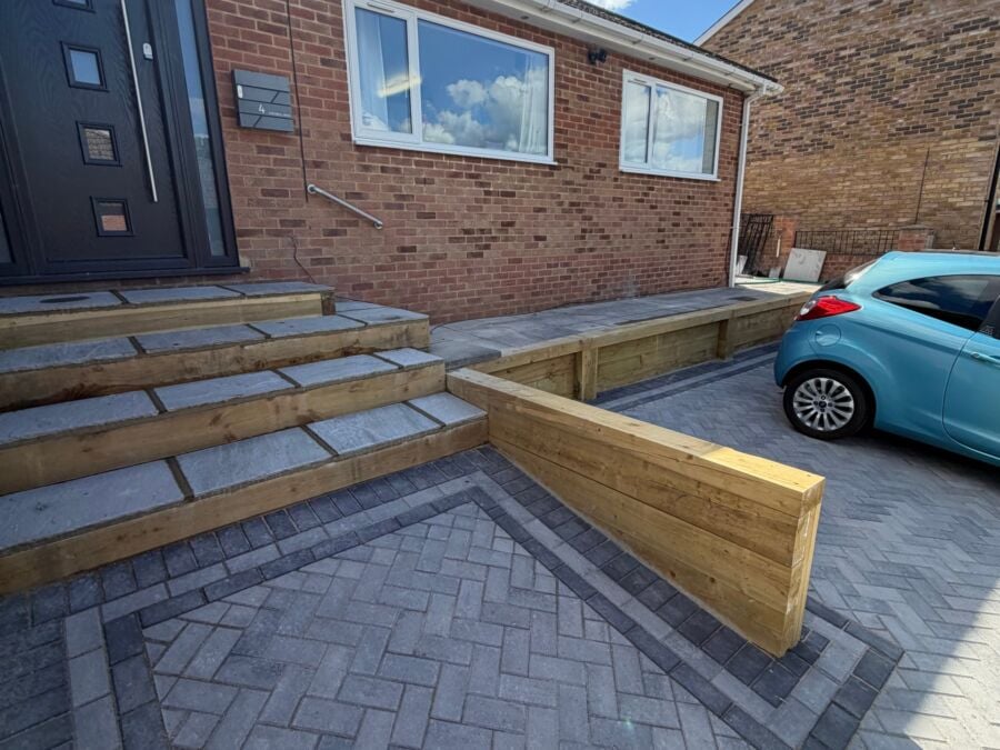 Herringbone block paved driveway with charcoal border, timber sleeper wall and stone steps
