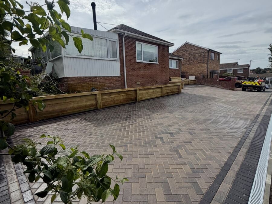 Large herringbone block paved driveway with timber sleeper edging and drainage channel
