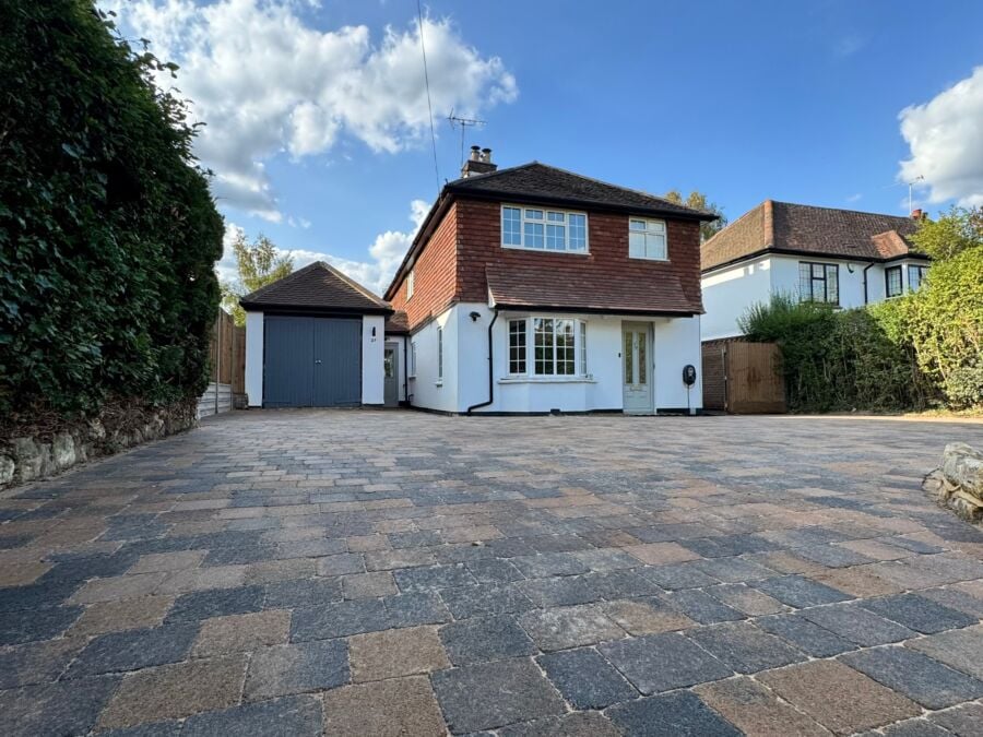 Block paved driveway in mixed brindle tones leading to a detached house and garage