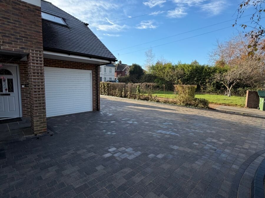 Dark block paved driveway in front of a garage with a white roller door