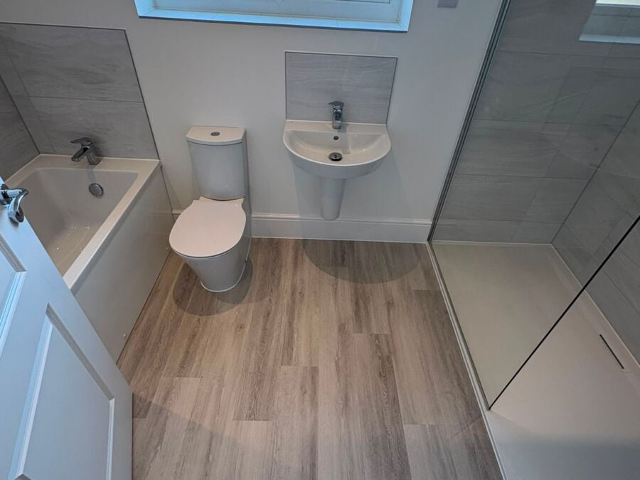 Loft bathroom with bath, basin, toilet, wood effect flooring and roof window