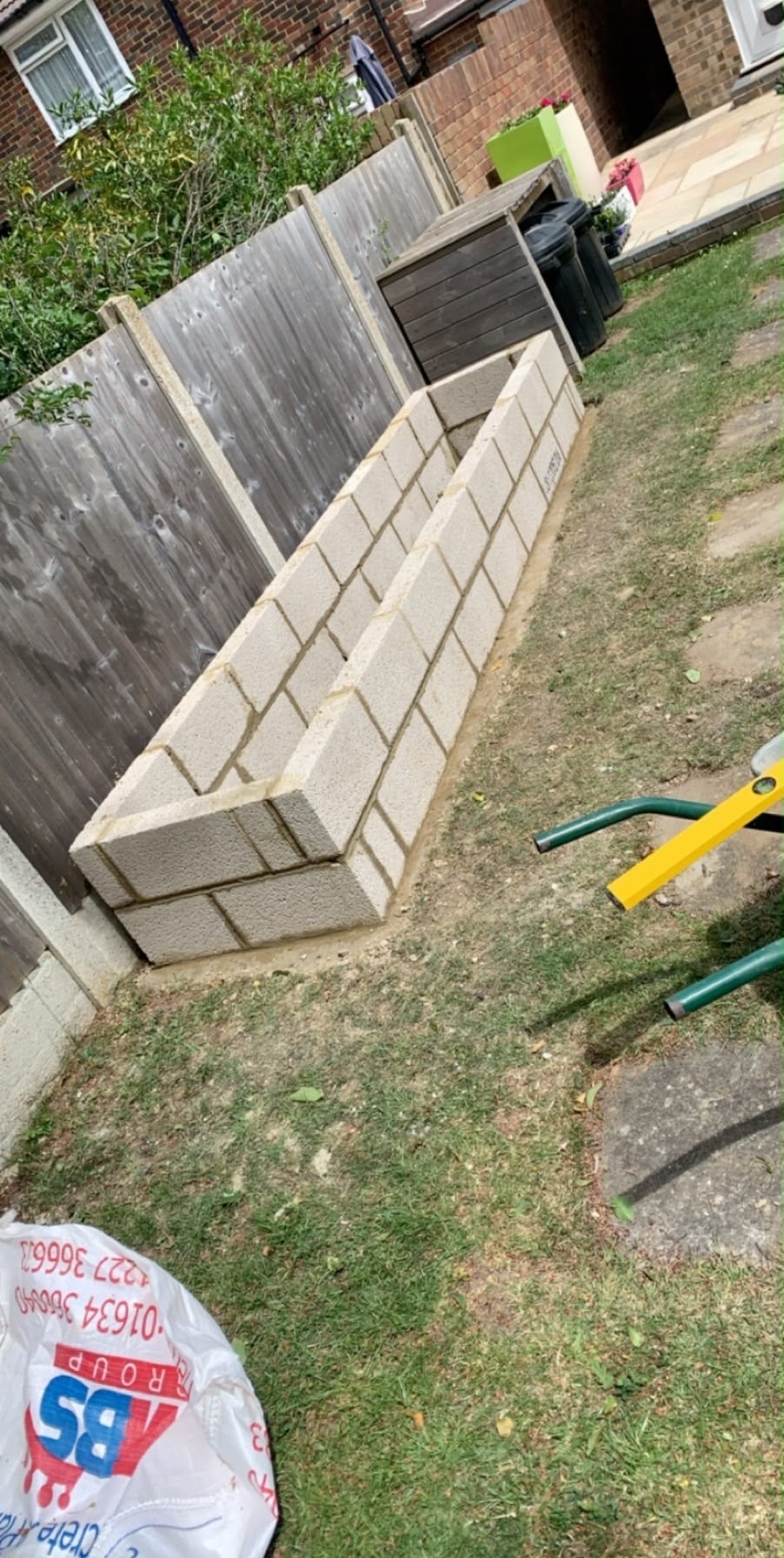 New concrete blockwork raised beds built along a garden fence