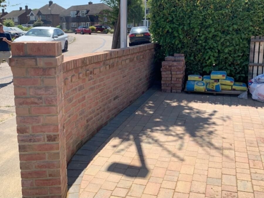 New red brick boundary wall with a capped pier beside a block paved drive