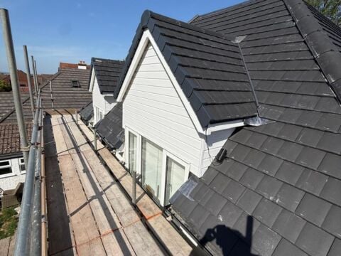New grey concrete tile roof with dormers, viewed from the scaffold