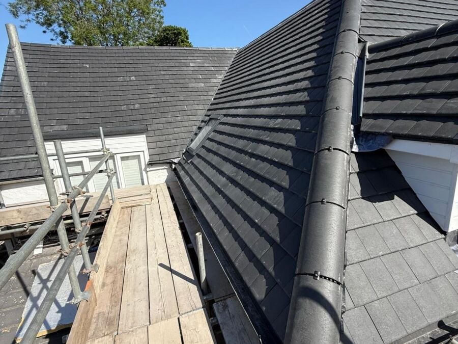 New concrete tile roof with ridge tiles and a dormer, seen from the scaffold