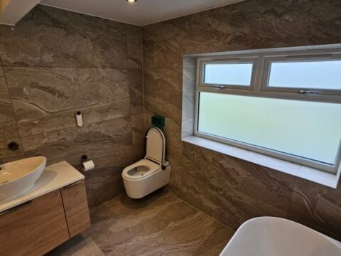 Modern bathroom installation featuring large format brown marble effect wall and floor tiles